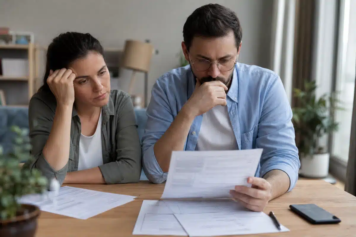 Couple préoccupé examinant des documents et factures